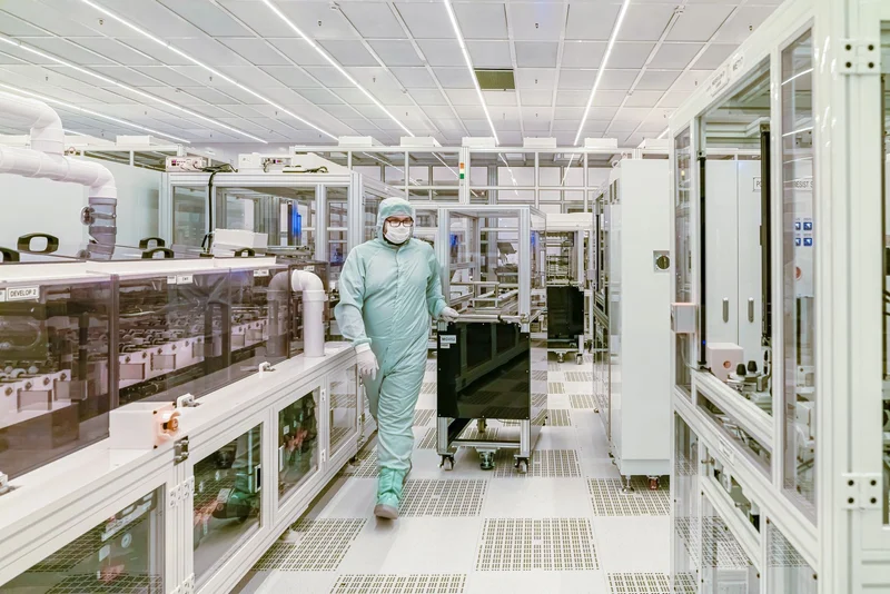 Engineer working with semiconductor wafer fabrication equipment in a cleanroom