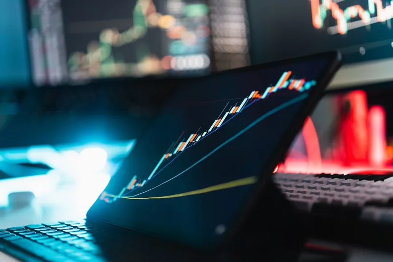 Silver bars beside a computer displaying a financial price chart